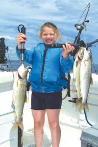 Left: While fishing with her dad Captain Darren of Tofte Charters, Katie caught her limit of Lake Superior lake trout all at the same time. All three trout bit at the same time and had to wait their turn as 7-year-old Katie reeled each one in.