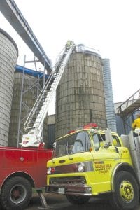 The Maple Hill and Grand Marais Fire Departments responded to a fire at Hedstrom Lumber Company on Friday, June 8 The fire was in one of the silos that hold wood byproducts to be burned in the lumber mill’s boiler. Firefighters climbed up the utility ladder on the side of the silo and also used the Grand Marais Fire Department’s ladder truck. Maple Hill firefighter Betsy Zavoral makes the climb up the 50-foot ladder to hand a saw to Grand Marais firefighter Aaron Mielke.