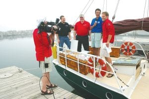 A six-person TV crew from WCCO/Channel 4 in the Twin Cities made a live broadcast from the Grand Marais Marina on June 18. It was part of a five-day tour of lake areas in Minnesota and Wisconsin in which the news crew visited area attractions and interviewed local residents and businesspeople. Standing on the Hjordis are (L-R) Andrew Smith and Sid Backlund of Sven & Ole’s and Anchor Frank Vascellaro and Chief Meteorologist Chris Shaffer of WCCO. The cameraman is Photojournalist Tom Aviles.