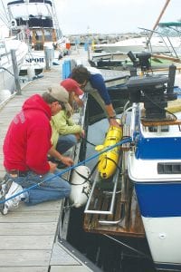 Bon voyage, Gitchi Gami! On Tuesday, June 19, researchers with the University of Minnesota-Duluth Large Lakes Observatory (LLO ) launched the Gitchi Gami, a submersible glider that collects data on its travels underwater. Captain Dave Williams helps Assistant Scientist Matt James and UMD graduate student Betsy Welsh load the glider onto the swim platform of his charter boat Fishin’ Chicks.