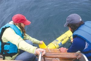 Above: Betsy Welsh and Matt James prepare to launch the Gitchi Gami into Lake Superior. Left: After being launched, the Gitchi Gami floated for only a few minutes and then slowly began its dive. The bright yellow, torpedo-shaped glider will quietly do its work about 20 feet below the water’s surface until it is recovered on June 29.