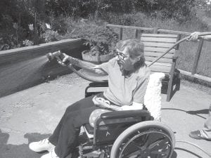 Marge Jamison stays busy watering the plants on the patios at the Care Center. She keeps a record of progress in the gardens.