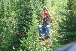 Above left: Participants are taught to slow and stop themselves as they near the platforms. However, it takes a little trial and error to get it right. Sky Guide Stephan Henkel shows exactly how it’s done. Above right: The view from Look Out Mountain—of Gunflint Lake and Canada beyond—is breathtaking. So too is the zip line which takes you 70 feet above the ground, skimming tree tops as you go. Courtney Koeneke of Johnsburg, IL launches off the platform, showing that even an almost-13-year-old can tackle the Towering Pines Canopy Tour.