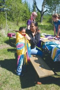 Above left: Students on the field trip were shown the regalia worn by Native Americans at special events such as powwows. Above right: After a picnic lunch on the Grand Portage powwow grounds, the Little Eagles drumming group played while students danced around the circle. All of the students were warmly invited to participate.