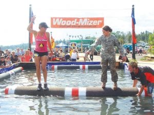 Eight-time log rolling world champion Jenny Atkinson shows a somewhat apprehensive National Guard member how to roll on the log. Atkinson and her husband Niel set up and run the Lumber Camp at the Fisherman’s Picnic.