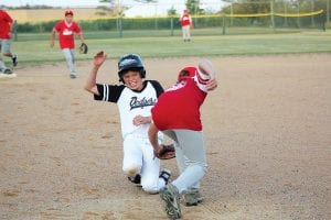 Left: Second baseman Ethan Sporn made a nice fielding play and threw the runner out at first base on this play. Above: Showing great poise and great effort, Lyndon Blomberg avoids a tag and scores on this play.