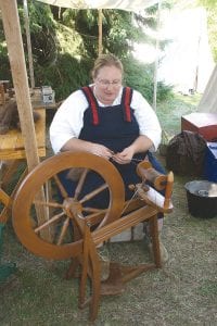 Left: Also hard at work at the voyageur encampment was Carol Cheney of Angora, MN. She was spinning fibers from the inner coat of a bison. She said it was challenging, as bison hair is shorter than sheep. However, it ends up being much softer, said Cheney. Above: This well-dressed couple enjoyed some time in the shade, discussing different fabrics of the 1800s at a textile workshop.