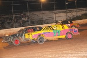 Above: Racing in car 77, Esten Nelsen of Grand Marais gets ready to blow by the field at Proctor Speedway. Left: Craig Horak (left) and Esten Nelson hold up trophies each have won this summer while racing stock cars. Nelson won first place and Horak placed third at the Proctor Speedway for the season in the Pure Stock point series. While the regular season has ended, both will race a few more times this fall before putting their cars away for the season.