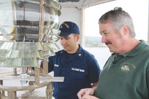 Preparing for change. The Fresnel lens, circa 1885, in the Grand Marais lighthouse was removed on Wednesday, September 5 and replaced with a modern, solar-powered light. U.S. Coast Guard EM2 Zalvidar and lampist Kurt Fosburg inspect the lens in its pedestal in the lighthouse tower before disconnecting it.