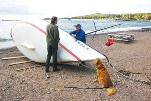 Monday, September 24 was a windy day. With the wind blowing fiercely out of the southwest, giant waves made their way straight into the harbor, pushing Scott Smith’s 23-foot Sonar sailboat onto the beach in front of the Lake Superior Trading Post. Smith got a call from the Sheriff’s Office telling him his boat had landed. He found that his 900-pound keel had sheared off where it was bolted to the bottom of the boat. He will be retrieving it from the bottom of the harbor. With temperatures in the 60s, both locals and tourists were walking out toward the lighthouse all day to watch the waves crashing into the breakwall. The wind shifted later in the day, coming out of the northwest, and then died down completely by evening. Pictured here are (L-R) Matthew Brown, Scott Smith, and Emma.