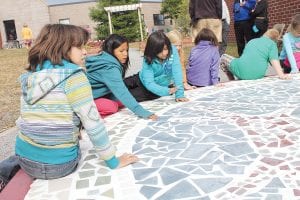 In September, there was a gathering at Sawtooth Mountain Elementary School to celebrate a new addition to the school courtyard—a beautiful tiled circle mosaic. After the dedication, students circled the mosaic for a close look at the symbols re-created in tile.