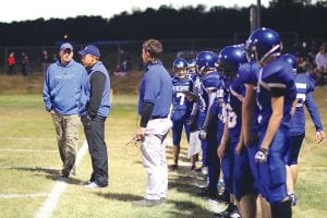 Above: Head coach Mitch Dorr and his assistant coaches Pat Eliasen and Bryan Carpenter had little to worry about in the game against Deer River. The Vikings' defense was stifling and the offense has never played better than they did against the Warriors. Left: With Richie Furlong clearing a path for him, Colin Everson had little trouble breaking away for a nice gain on this carry. Everson rushed for five touchdowns against Deer River and played great on defense.