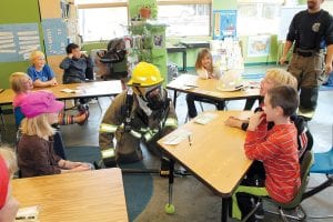 The Grand Marais Fire Department visited Great Expectations School on Monday, October 8. Right: Firefighter Gary Nesgoda, in turnout gear, demonstrated how a firefighter coming to the rescue in a fire would appear. Below: Jessen got to hold a heavy Halligan bar, a multipurpose firefighting tool.