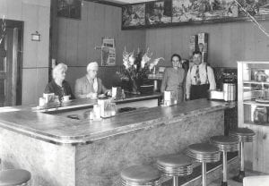 This is the interior of the Kaffe Stuga in Grand Marais in the early 1950s. It was in the building that is now South of the Border Café and operated along with a Mobil gas station that eventually became Shold & Lovaas Mobil. (L-R) Mrs. Anna Hussey, Mrs. Ruth Gilbertson, and owners Freda and Andrew Shold. “Kaffe Stuga” means “little coffee house” in Swedish. As a young adult, Andrew Shold immigrated to Grand Marais from the Swedish province of Dalarna as his wife Freda’s parents had also done.