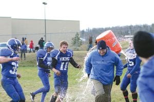 Top: Players give a happy Head Coach Mitch Dorr an early (and cold) bath after their victory over Blackduck. Left: With the ball tucked tightly in his arm, Viking quarterback Kale Boomer sprints around the end for another big gain against Blackduck. For the game Boomer rushed for 198 yards and scored three touchdowns. Above: Wide receiver Joe Borud looks like a choirboy next to the Vikings linemen. Looking rough, tough and ready to rumble were Justin Goldstein (in back with Mohawk) Dakota Sorlie, Clay Johnson and Jonny Jacobsen (Mohawk). The line utterly dominated the play in the game against Blackduck.