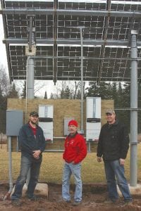 Jonathan Hedstrom of Hedstrom E&E, Brian Bennett of Outback Solar Electric and David Bartz of Hedstrom E&E, stand next to the inverters at the 39-panel solar photovoltaic installation at Gunflint Hills Golf Course. The array, recently installed by Bennett, can produce enough electricity for two typical households or three energy efficient households for a year. Hedstrom E&E connected the array to the grid, operated by Arrowhead Electric Cooperative, Inc.