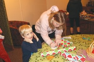 Left: Little Kaj got some help wrapping a gift for his mom from Girl Scout Molly. Above: The Girl Scouts also hosted a tasty pancake breakfast. Ready to fill a plate is Emma and Haley.