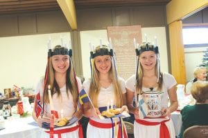 What is better than one St. Lucia to bring light to the darkest winter day? Three young ladies as St. Lucia. (L-R) Sarah Toftey represents Norway, Hannah Toftey represents Sweden and Tarin Hanson represents Finland.