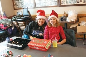 Above left: Jasmine and Jade did a great job as Christmas elves. They sold tickets and operatedcarnival games. Above right: Friends Ryan (front) and Logan enjoyed playing the “icefishing” game.