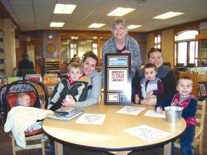 Grand Marais Library Director Linda Chappell was delighted to receive the plaque recognizing the library’s 5-star status last week. When Chappell asked some families at the library if they would be willing to be in a picture announcing the award, the answer was a resounding, “Sure, we love the library!” In the photo are (L-R) Cooper, Danny and Ceira Garcia, Library Director Chappell, Carrie, Birk (on Carrie’s lap) and Lute Jansen.