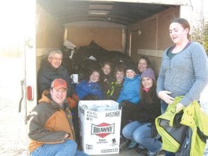 When the call went out that the Damiano Center in Duluth was in need of winter coats, the Bethlehem Lutheran Church youth group went into high gear and collected nearly 400 winter coats and jackets donated by residents of Cook County. The coats will be given to those who can’t afford to purchase coats for the winter. Left: Cuddled in the bags and leaning against the boxes are some of the people who worked on the project. (L-R) Mike Prom, Lief Lunde (behind), Abby Prom, Elsa Lunde, Josh Prom, Ella Sporn, Sue Prom, Sissy Lunde and MaeAnna LaFavor. Below: The crew takes a break from packing.