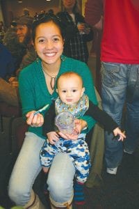 Above left: Rachael Seim and her baby, Aitan, looked pretty happy with whatever they were eating at the chili cook-off at St. John’s Catholic Church on February 23. Above right: Grand Marais Lion Rosemary Lamson samples one of the 21 different kinds of chili at the event.