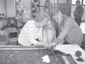 Community members of all ages worked together at Bethlehem Lutheran Church in March to make quilts for Burmese refugees in Thailand. Pastor Mark Ditmanson challenged the community to make 25 quilts, but the men, women, and children involved in the project exceeded their goal by making 30 quilts. (L-R) Carol Berglund, Greta Roth, and Stephanie Radloff work together.