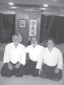 Left: Craig Waver (left) and his son, Steve, flank guest instructor Zenko Okimura, Shihan, 7th Dan, Chief Instructor of the World Aikido Aikikai Federation. Zenko judged the students testing for belts on Saturday. His comments were insightful and sometimes very funny. Above: (L-R, front) Members and family friends of the Grand Marais Dojo: Steve Frykman, Craig Waver, Steve Waver, Gederah Waver, Shihan Zenko Okimura, Joanne Smith, Joe Copeland and Randy Spry. (L-R) Westin Waver, Nancy Waver and Cathy Waver.