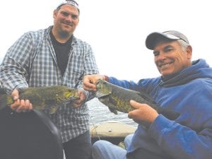 The Hokans family of Hastings, Minnesota had a great day of fishing on a local lake with Joe Carlson of Joe’s Inland Guide Service. Above: Mark Hokans compares the very nice 16.5- inch bass with the 18-incher caught by his dad, Chuck Hokans. Left: Erik Hokans shows off the 22-inch walleye he caught while fishing with his dad, Mark Hokans (behind) and grandfather on Saturday, June 15.