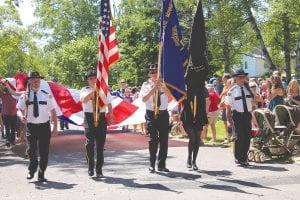 Right: The American Legion Post 413 Color Guard led the Tofte 4th of July parade along the Tofte Park Road on Independence Day. Below: There were dozens of parade entries. One of the most patriotic and colorful was the Lamb’s Resort marchers.