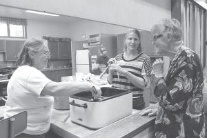 The Cook County Historical Society hosted its annual fishcake dinner on Friday, June 28. The event was very well-attended with no left-over fishcake batter! Top: Bev Pratt and Historical Society Director Carrie McHugh serve up a plate of fishcakes for Thelma Hedstrom. Left: Historical Society volunteer Pat Zankman talks historical trivia with Dorie Carlson. Above: News-Herald Editor Rhonda Silence and Katie Anderson were the lucky winners of historical society coffee mugs. The lovely mugs feature Bally’s Blacksmith Shop.