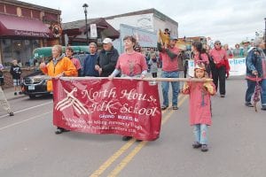 Above: The Friday night parade of teams is always fun. North House Folk School was one of the parade participants. Little Olya (on the right) is not old enough to paddle a dragon boat yet, but she did a great job helping carry the North House banner.