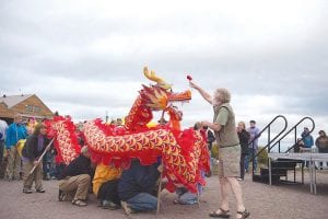 Right: Grand Marais City Councilor Tim Kennedy had the honor of waking the dragon. As he sprinkled the colorful beast with cool, fresh, Lake Superior water, it came to life and gave a roar, opening the 10th Annual North Shore Dragon Boat Festival activities.