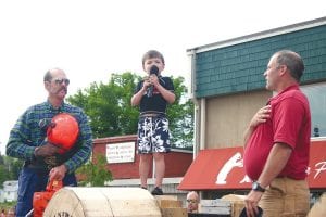 Right: With great feeling and singing on key, four-year-old Behrent “Bear” Atkinson sang the national anthem before the saw sports began on Saturday afternoon. With Bear is Paul Higgins (right) and Bear's dad Niel Atkinson.