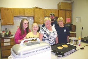 Above: These pancake servers were full of enthusiasm at the August 17, 2013 John Schroeder Community Fun Day pancake breakfast sponsored by the Schroeder Fire Department. (L-R) Jamie Johnson, Casey Johnson, Liddy Pearson, Waylon Christiansen, and Deb Johnson. Right: Shirley Bierbaum and Skip Lamb examine old photos on a walking tour of the Cross River area.