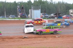 Left: Racing in car No. 26, Craig Horak helps to “straighten out” the Carlson car, which got turned sideways during a Pure Stock car race at the Proctor Speedway. Because of all of the safety features, drivers rarely get hurt. But the cars do tend to slide on the dirt tracks, and contact, although unintentional (usually) is frequent. Below: Esten Nelson, in car No. 77, and Horak in car No 26, both give the thumbs up sign. The two Grand Marais men are both in the top echelon of Pure Stock racecar drivers in the Northland.