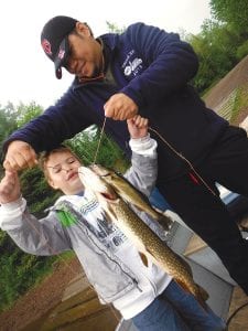 Left: Kiko Marcelino of Minneapolis doesn’t look quite sure what to do with the fish on his stringer. Kiko and his dad Manuel were fishing with Joe Carlson of Joe’s Inland Guide Service when they caught this 25-inch northern and 13-inch walleye. Kiko was excited about the first fish he had ever caught.