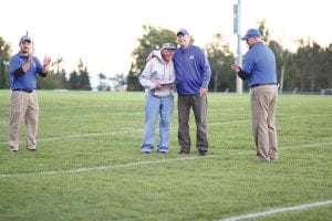 With Bryan Carpenter (left) and Mike Boomer looking on, football Head Coach Mitch Dorr gives former Viking football announcer Walt Mianowski a hug after presenting Mianowski with a plaque commemorating his 29 years as the voice of the Vikings. The award was made before the game against the East Central Eagles on Friday, September 13.