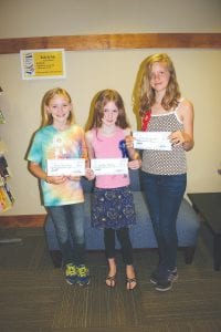 These three young writers were winners of a recent essay contest for youth ages 10-13 at the Grand Marais Public Library. They wrote about libraries and reading, using lots of logic, personal examples, and imagination. Lance Johnson, who envisioned and sponsored the contest, and Juvenile Librarian Patsy Ingebrigtsen, who organized the contest, were on hand on September 13, 2013 to deliver the $75, $50, and $25 prizes for the top three essayists. (L-R) Robin Henrikson (3rd place), Jorden Herrly (1st place), and Ellen Callender (2nd place).