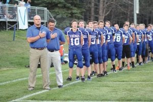 Left: Lining up for the National Anthem, coaches, players and fans pay tribute to the flag and all it stands for. Above: Leo Johnson scrambled for a short gain against Deer River on this play.