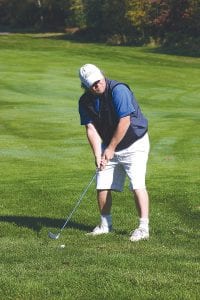 Above: Marshal “Dinky” Pederson played a ball from the fairway, chipping it close to the hole. Left: While officials and Chris Lavigne, leaning on his putter, looked on, Lavigne’s playing partner putted to see if he could win a prize on the first hole.