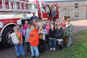 Members of the Grand Marais and Hovland Volunteer Fire Departments visited Grand Marais schools on Thursday, October 10 as part of National Fire Prevention Week. Top: The Sawtooth Mountain kindergarten kids were happy to pose by the fire truck. Above: There were lots of questions! Left: Cade looked right at home in the fire truck.