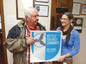 Grand Marais Mayor Larry Carlson, left, accepts a sign designating the city a “Bicycle Friendly Community” from Kristin DeArruda Wharton, coordinator of the Cook County Active Living Committee. The award is bestowed by the League of American Bicyclists and recognizes a community’s commitment to improving conditions for bicycling through investment in promotion, education programs, infrastructure and pro-bicycling policies.