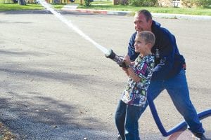 October 6-12 was National Fire Prevention Week and local fire departments visited area schools to talk to elementary school students about fire safety. The visit includes the opportunity to see a fire engine up close. Lee Jahnke of the Tofte Volunteer Fire Department gives Wyatt a chance to try using a fire hose.