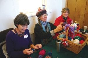 (L-R) Nancy Haarmeyer, Elise Kyllo, and Bonnie Gay Hedstrom make pom-poms at the “hands-on” table at the Northwoods Fiber Guild holiday sale at the Grand Marais Art Colony on December 7, 2013.