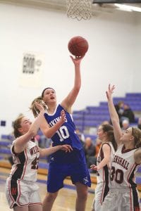 Far left: Lily Gruber- Schulz (10) ignored the defensive pressure and scored 2 points against Wrenshall. Above: Emily Jacobsen dribbled the ball into the paint, driving hard to the hoop before dishing off to a ponytailed Breanna Peterson (left) who hit for two points against the Wrenshall Wrens.