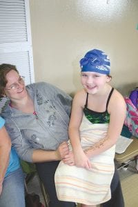 Above: Taking a break from her competition, a happy Grace Richie sits on her aunt Nicole Bockovich's lap and gets some encouragement. Right: Waiting for their commands, two young racers get ready to backstroke to the other end of the pool as fast as they can.