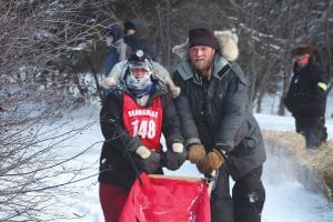 Above: Erin Altemus of Grand Marais was met by her handler-husband Matthew Schmidt after crossing the Tofte mid-distance finish line. Altemus and her Nuannaarpoq Kennel dogs finished in fourth place. Left: Mushers— and canine athletes like this fellow—got some much-needed rest at the Sawbill checkpoint on Monday afternoon.