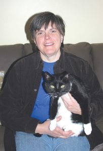 Sue Hennessy is shown here with her cat Bo. Bo is a great help at home but not much help at the Arrowhead Center for the Arts (ACA) where Sue works to put on plays and other performances. Sue has been the Grand Marais Playhouse director since 2002 and she is in dire need of help with any and all duties associated with putting on future great performances like the ones that we have grown accustomed to throughout the years.