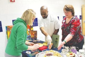 Stephanie Radloff samples some of the delectable cedar planked salmon and sweet scones offered by Naniboujou Lodge. Helping her is Chef Steven Brown and Diane Stoddard.